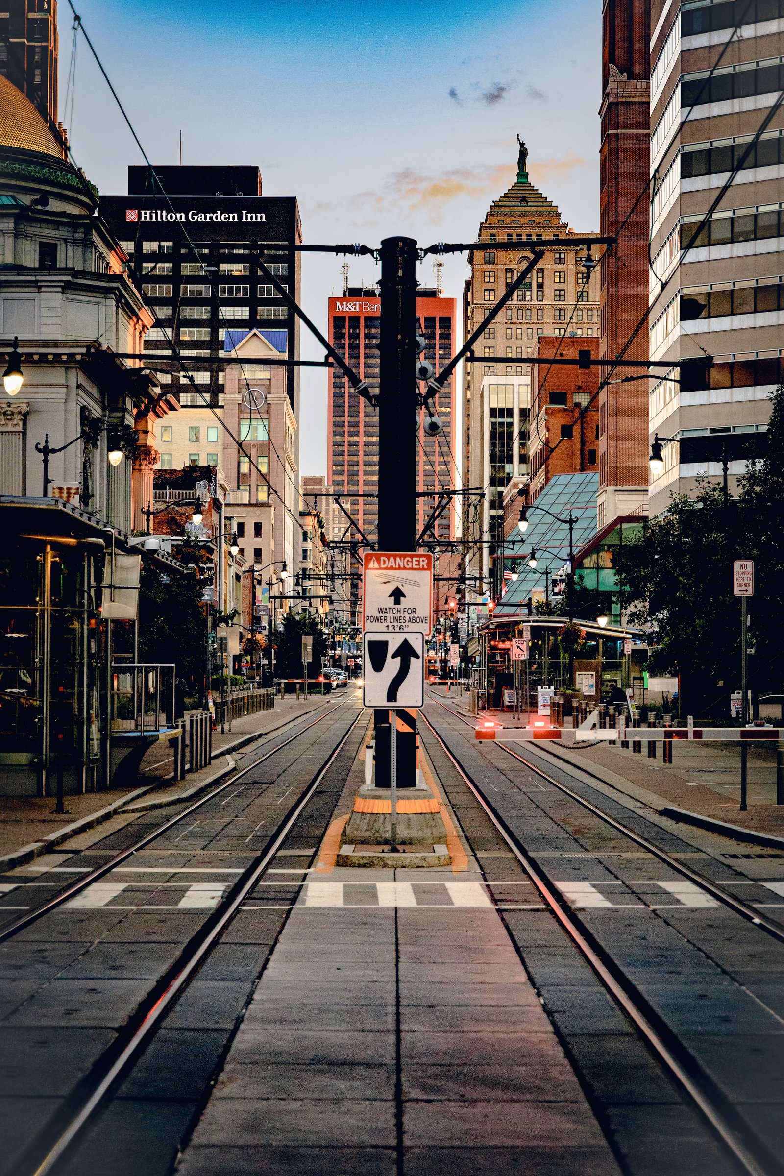 A view down a set of parallel train tracks in a city street, flanked by tall buildings.